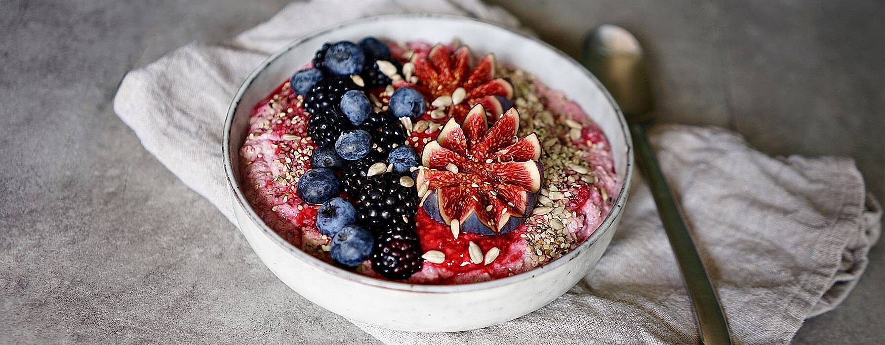 Bowl mit Muesli garniert mit frischen Brombeeren, Heidelbeeren, Feigen und Saaten